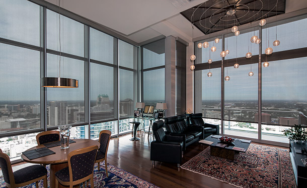 Modern gray roller shades filtering light across floor-to-ceiling windows in a contemporary interior
