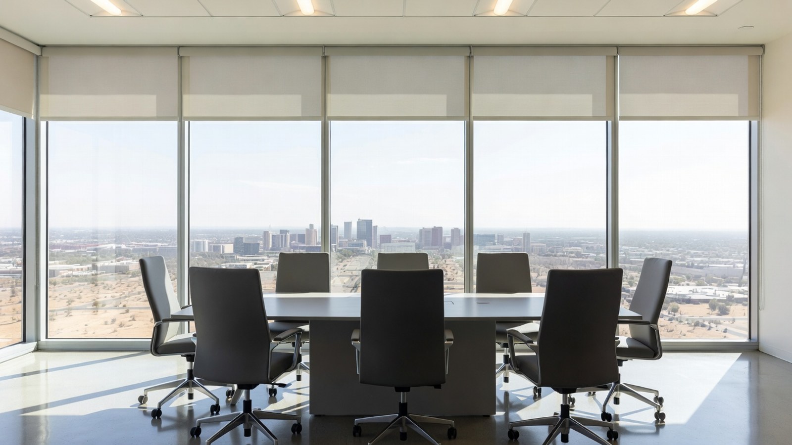 Commercial roller shades controlling glare in a modern Phoenix office conference room.